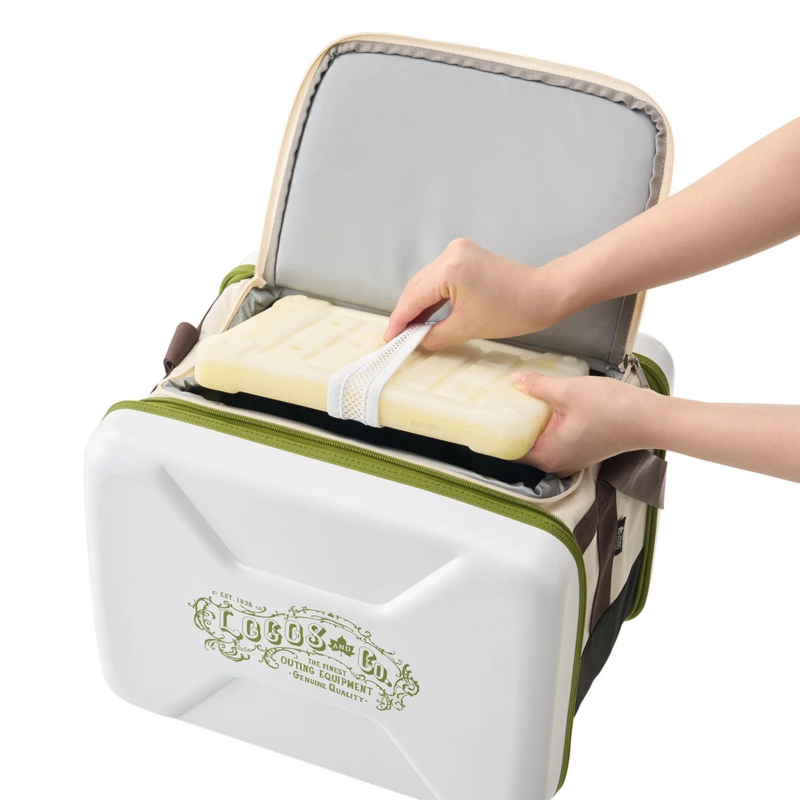 白いと緑のクーラーボックスに、人が黄色の保冷剤を入れている様子