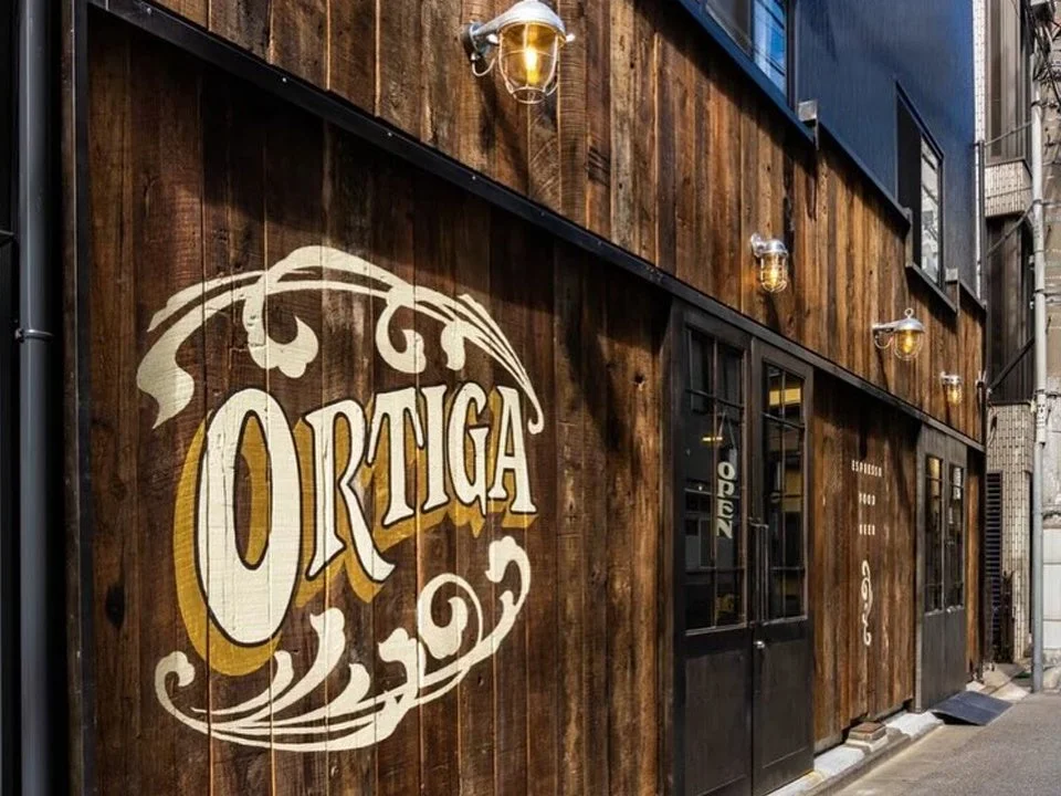 木目調の壁に「ORTIGA」のロゴが大きく描かれた店舗の外観