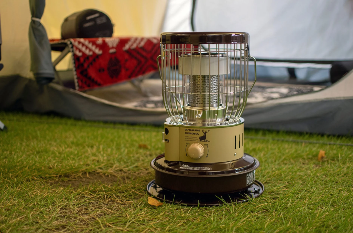 芝生に置かれた小型ストーブ、テントとブランケット