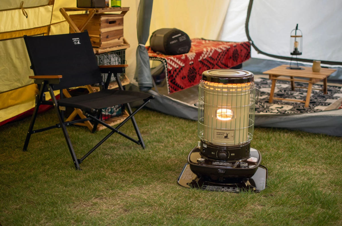 テントのそばにキャンプ用チェアと灯油ストーブが置かれたキャンプシーン