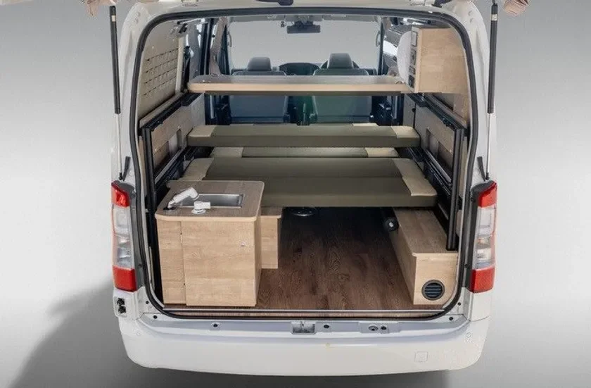 白いバンの後部内装、ベッドと簡易キッチン